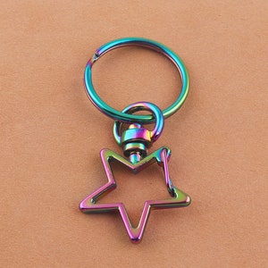 May include: A rainbow iridescent metal key ring with a star-shaped hook. The key ring has a round ring for attaching keys.
