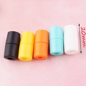 May include: Five plastic cord end stoppers in black, yellow, orange, light blue, and white. Each stopper is 20 mm long.