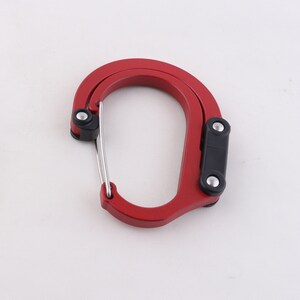 May include: A red metal carabiner with a black plastic clip and a silver spring-loaded gate.