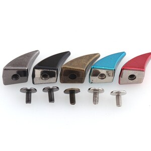 May include: Six metal claw-shaped studs in different colors, including silver, black, bronze, blue, and red, with matching screws.