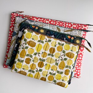 Puede incluir: Cuatro bolsas de tela acolchadas con diferentes patrones. La bolsa superior tiene un patr&oacute;n geom&eacute;trico amarillo y marr&oacute;n con un dise&ntilde;o acolchado. La segunda bolsa tiene un patr&oacute;n floral azul oscuro y verde. La tercera bolsa tiene un patr&oacute;n floral gris y blanco. La bolsa inferior tiene un patr&oacute;n floral rojo y blanco.