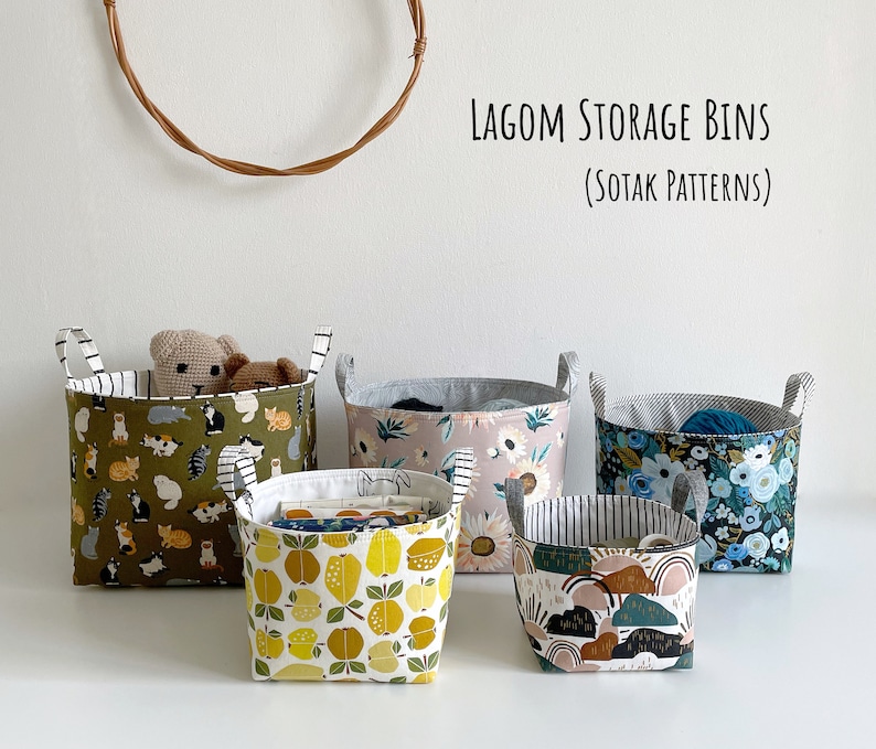 May include: Five fabric storage bins with different patterns. The bins are made of a soft, durable fabric and have a sturdy construction. The patterns include cats, flowers, and geometric shapes. The bins are labeled "LAGOM STORAGE BINS (SOTAK PATTERNS)".