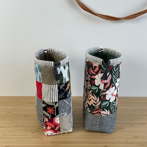 Pode incluir: Duas bolsas de cord&atilde;o de tecido com designs de patchwork. Uma bolsa tem um padr&atilde;o floral em tons de vermelho, branco e verde sobre um fundo verde escuro. A outra bolsa tem um design de patchwork com v&aacute;rios tecidos em tons de vermelho, branco, preto e marrom.