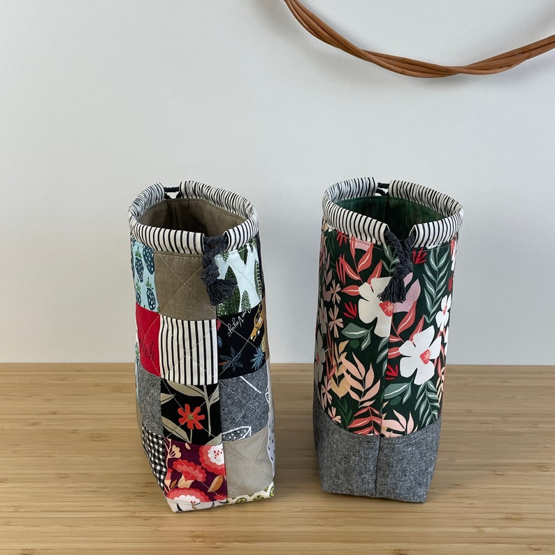 Pode incluir: Duas bolsas de cord&atilde;o de tecido com designs de patchwork. Uma bolsa tem um padr&atilde;o floral em tons de vermelho, branco e verde sobre um fundo verde escuro. A outra bolsa tem um design de patchwork com v&aacute;rios tecidos em tons de vermelho, branco, preto e marrom.