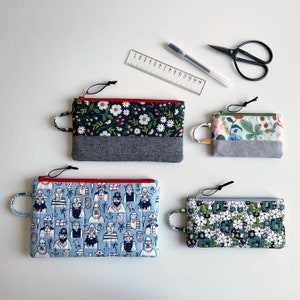 May include: Four different zippered pouches with various patterns. The pouches are made of fabric and have a zipper closure. The patterns include a floral design, a nautical design, and two different floral designs.