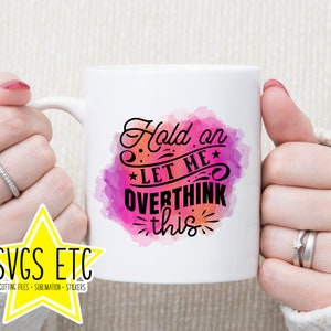 May include: White ceramic mug with a pink and purple watercolor design. The text "Hold on *Let me* Overthink this" is written in black on the mug.