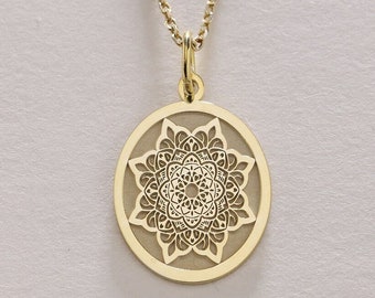 Könnte beinhalten: Eine goldene Halskette mit einem runden Anhänger, der ein detailliertes Mandala-Design zeigt.