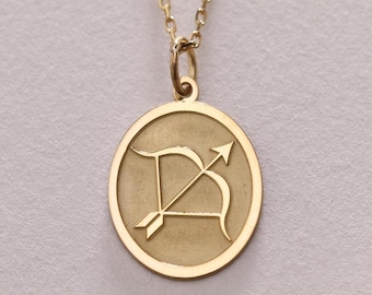 May include: Gold necklace with a round pendant featuring the Sagittarius zodiac symbol, an archer with a bow and arrow.