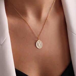May include: A gold chain necklace with a round pendant featuring a scorpion design.