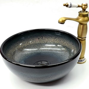 May include: A black ceramic vessel sink with a gold-toned faucet. The sink has a speckled, textured finish and a round shape.