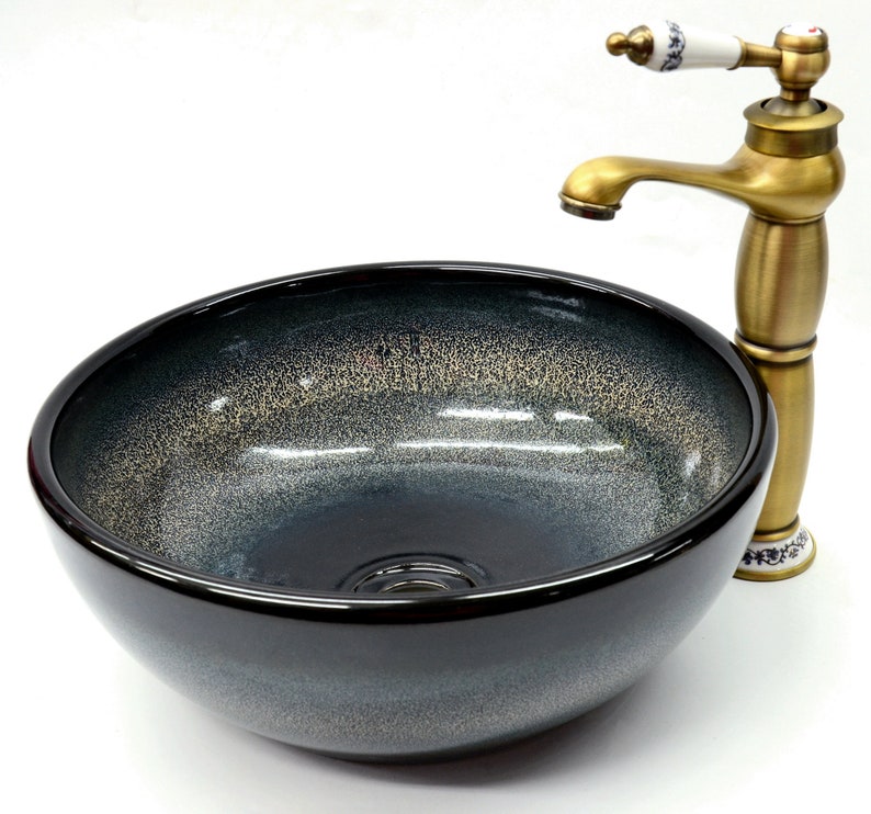 May include: A black ceramic vessel sink with a gold-toned faucet. The sink has a speckled, textured finish and a round shape.