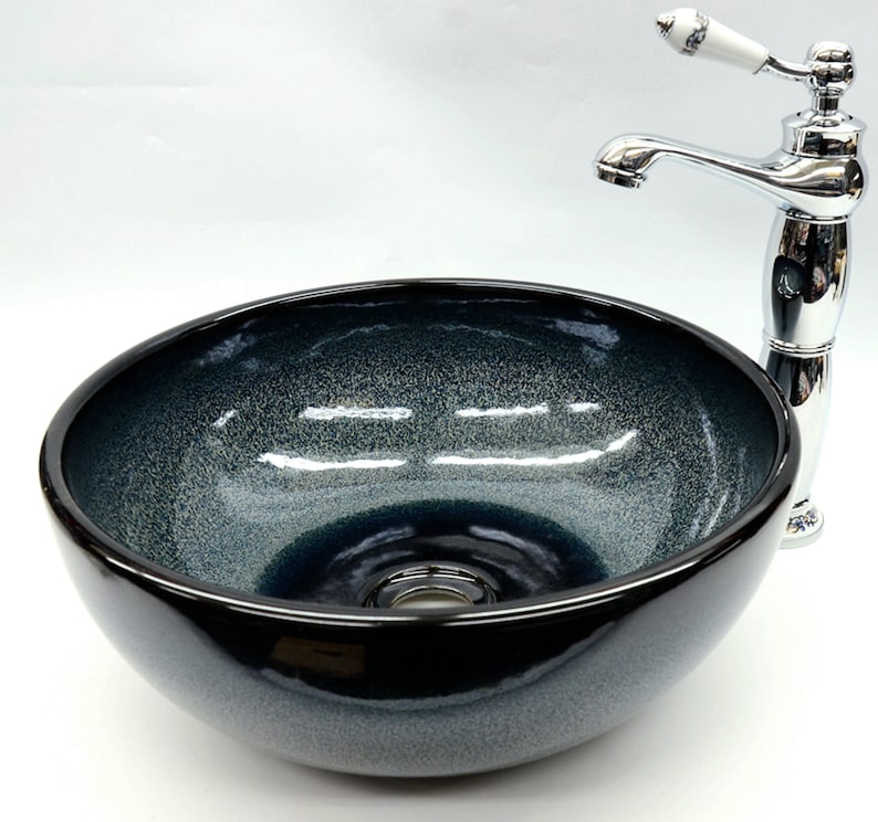 May include: A dark blue ceramic vessel sink with a chrome faucet. The sink has a textured, speckled finish and a round shape.