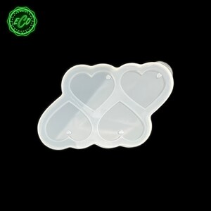 Puede incluir: Un molde de silicona transparente en forma de cuatro corazones. Este molde está diseñado para manualidades y proyectos de arte con resina. El producto se presenta sobre un fondo negro, resaltando su forma y diseño.