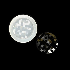 Puede incluir: Un molde de silicona blanco con un patrón a cuadros en el interior. Junto a él hay una pieza de resina a cuadros negros y plateados.