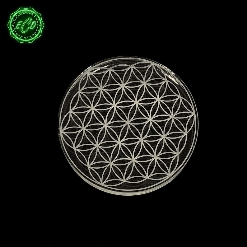 May include: A clear glass coaster with a white flower of life design.