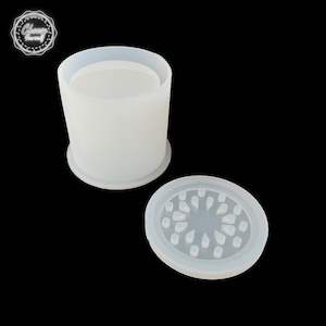 May include: A white silicone mold for making a small round container with a decorative lid. The lid has a circular pattern of small raised dots.