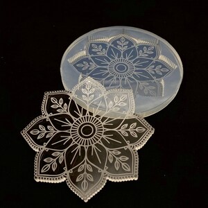 May include: A clear silicone mold with a detailed mandala design. The mold is shown with a resin casting of the mandala design.