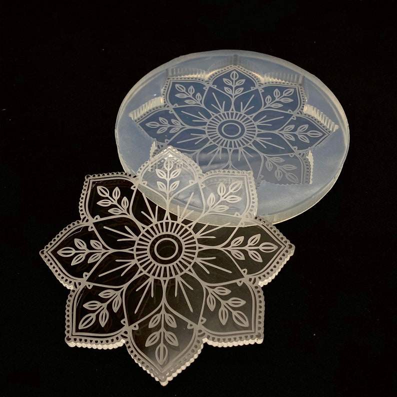May include: A clear silicone mold with a detailed mandala design. The mold is shown with a resin casting of the mandala design.