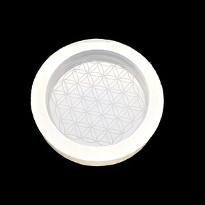 May include: White silicone mold with a raised flower of life design. The mold is round and has a raised rim.