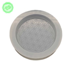 May include: A white silicone mold with a raised flower of life design. The mold is round and has a raised edge.