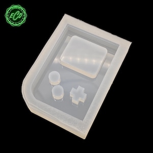 May include: A clear silicone mold shaped like a handheld video game console. The mold has a rectangular screen, two round buttons, and a plus-shaped button.
