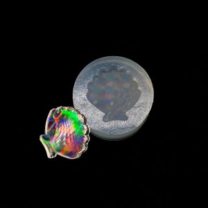 May include: A clear silicone mold with a seashell design. A iridescent seashell is shown next to the mold.