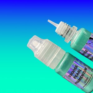 May include: Two small squeeze bottles containing shimmering mint green pigment. Each bottle features a clear plastic cap and a holographic label with the text CHOOSE PEARL PIGMENTUM 10ml and the website address www.chooseyours11.com printed on it.