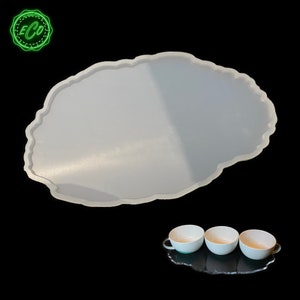 May include: White silicone resin tray with an irregular, organic shape. The tray is designed to hold three small cups or bowls. The cups are white with a glossy finish.