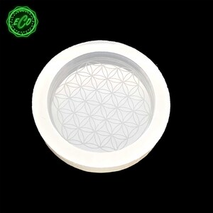 May include: White silicone mold with a raised flower of life design. The mold is round and has a smooth surface.