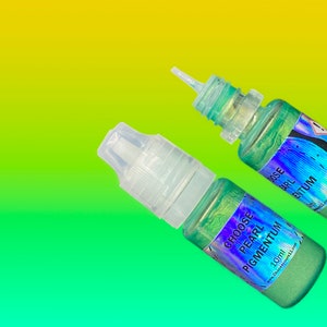 May include: Two small plastic squeeze bottles containing shimmering green liquid pigment. Each bottle features a clear cap and a holographic label with the text CHOOSE PEARL PIGMENTUM 10ml and the website address chooseyours11.com printed clearly.