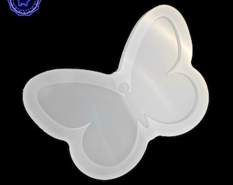 May include: A translucent, butterfly-shaped silicone mold with a smooth, glossy finish. The mold features a defined outline of butterfly wings and a central body section, designed for casting or crafting purposes on a black background.