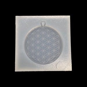 May include: A clear silicone mold for making resin jewelry. The mold is shaped like a circle and features a raised design of a flower of life pattern.