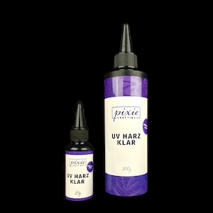Könnte beinhalten: Zwei Flaschen mit klarem UV-Harz, eine mit 25 g und eine mit 200 g. Beide Flaschen haben einen schwarzen Deckel und ein violettes Etikett mit dem Text "pixie crafting UV Harz Klar" und der Größe in Gramm.