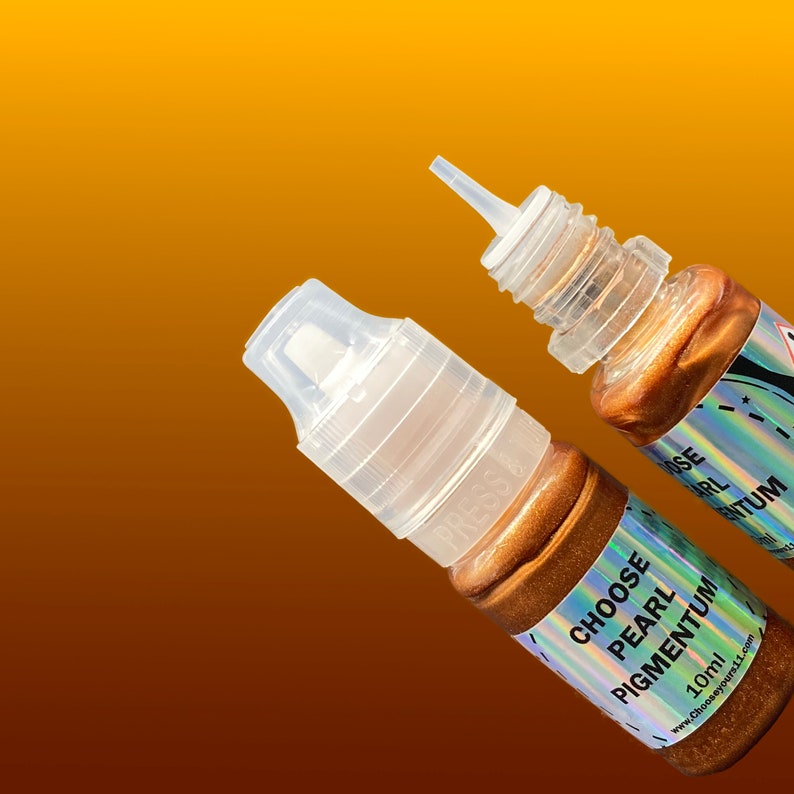 May include: Two small squeeze bottles containing bronze-colored liquid pigment. Each bottle features a clear plastic cap and a holographic label with the text CHOOSE PEARL PIGMENTUM 10ml and the website address chooseyours11.com printed clearly.