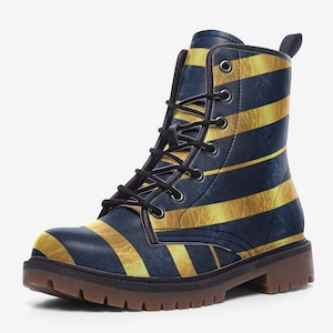 May include: A pair of combat boots with a navy blue and gold striped pattern. The boots have black laces, a brown sole, and a small pull tab at the back. The boots are made of a leather-like material.
