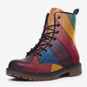 May include: A colorful, patchwork-style combat boot. The boot features a mix of red, purple, blue, yellow, green, and brown panels with a textured pattern. It has black laces and a brown sole.