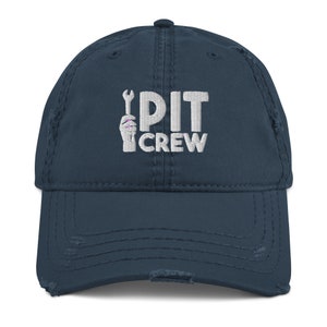 May include: A navy blue distressed baseball cap with white embroidery that reads "PIT CREW" and a wrench graphic.