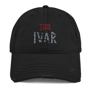 May include: Black distressed baseball cap with the text "KOM IVAR" embroidered in red and gray.