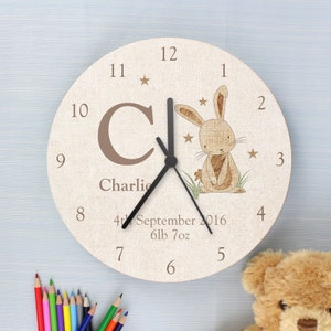 Peut inclure: Une horloge de nurserie personnalisée avec un fond beige et une illustration de lapin brun. L'horloge présente une grande lettre brune "C" et le nom "Charlie" imprimé en dessous. L'horloge comprend également la date "4th September 2016" et le poids "6lb 7oz".