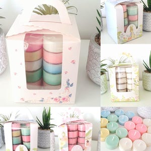 Peut inclure: Un ensemble de bougies chauffe-plat de couleur pastel dans une boîte en plastique transparente avec un motif floral. La boîte a une poignée et est entourée de verdure. Les bougies chauffe-plat sont disposées en piles de trois, chaque pile présentant une couleur différente.