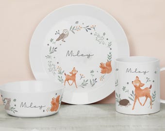 Puede incluir: Un juego de vajilla blanco para niños con plato, cuenco y taza. Cada pieza está decorada con animales del bosque, como un ciervo, una ardilla y un búho, y el nombre "Miley". El conjunto tiene un diseño caprichoso inspirado en la naturaleza.