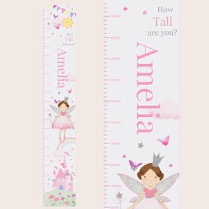 May include: A white and pink growth chart featuring a fairy with a crown and wings. The chart has a pink castle, flowers, and butterflies. The text "How Tall are you?" and "Amelia" are printed on the chart.