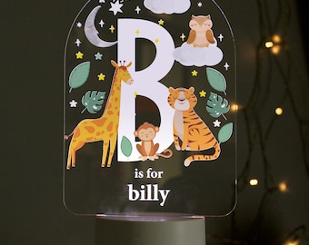 May include: A white acrylic night light shaped like an arch with a white letter B, a giraffe, a tiger, a monkey, and an owl. The light has a white base and the text "B is for billy" is printed below the letter.