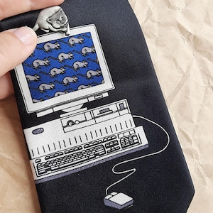 May include: A black tie featuring a white computer, keyboard, and mouse design. The computer screen displays a pattern of grey mice on a blue background. A small silver mouse figurine sits atop the computer.