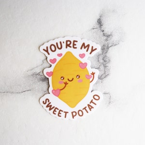 May include: White sticker with a cartoon sweet potato with a smiling face and pink hearts. The text "You're my sweet potato" is written around the sweet potato.