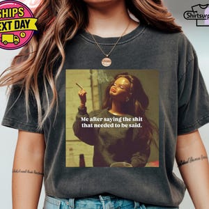 K&ouml;nnte beinhalten: Dunkelgraues T-Shirt mit einem Aufdruck einer rauchenden Frau und dem Text "Me after saying the shit that needed to be said." Das T-Shirt hat eine lockere Passform und kurze &Auml;rmel.