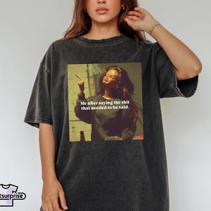 K&ouml;nnte beinhalten: Dunkelgraues T-Shirt mit einem Aufdruck einer Frau mit Zigarette und dem Text "Me after saying the shit that needed to be said." Das Shirt hat eine lockere Passform und kurze &Auml;rmel.