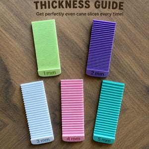 May include: A set of five rectangular plastic cane slice thickness guides in light green, purple, light blue, pink, and teal. Each guide features horizontal ridges and is labelled with its specific thickness from 1 mm to 5 mm. The text CANE SLICE THICKNESS GUIDE is printed at the top.