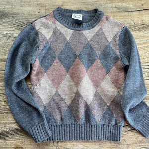 May include: A gray sweater with a diamond pattern in shades of pink, brown, and gray. The sweater has a crew neck and long sleeves.