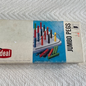 May include: A box for a children's game called "Jumbo Pegs" by Ideal School Supply Company. The box shows a colorful peg game with a blue, white, and yellow background. The box has the text "100 PEGS 5 COLORS" printed on the bottom.
